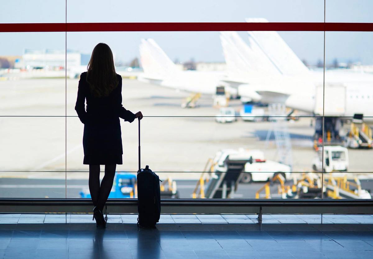 Young woman in the airport, looking through the window at planes